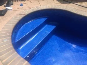 Swimming pool with blue interior and steps, brick deck surrounding the empty pool