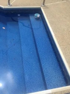 Empty swimming pool with blue textured interior and steps visible from above