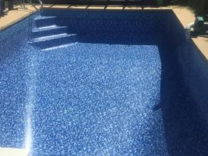 Empty swimming pool with blue textured interior and steps visible on the left side