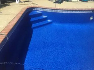 Swimming pool with bright blue water and brick deck during renovation or maintenance work