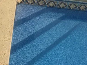 Pool edge with blue tile mosaic pattern and decorative border trim
