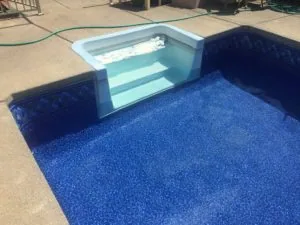 Swimming pool under construction showing blue interior coating and light blue bench seating area