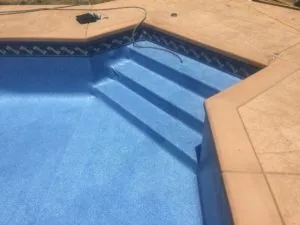 Empty swimming pool with blue interior and concrete deck surrounding it