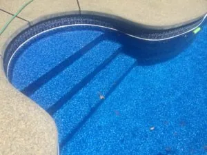 Swimming pool with blue textured floor and three step tread marks visible, viewed from above