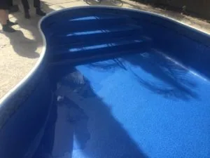 Empty in-ground swimming pool with blue interior and white trim