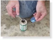 Two hands applying adhesive to a pool patch on concrete surface