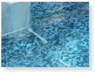 Water leaking from pool wall into blue swimming pool water
