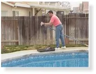 Person using a long pole to clean a swimming pool