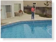 Person standing on pool deck next to rectangular swimming pool with blue water