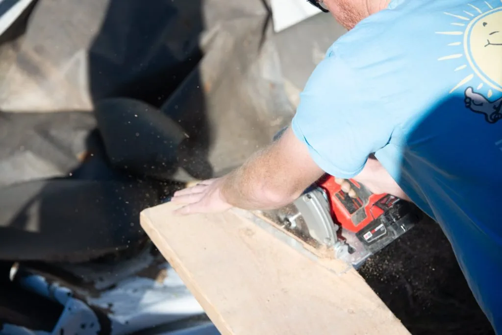 Person using circular saw to cut wood plank outdoors