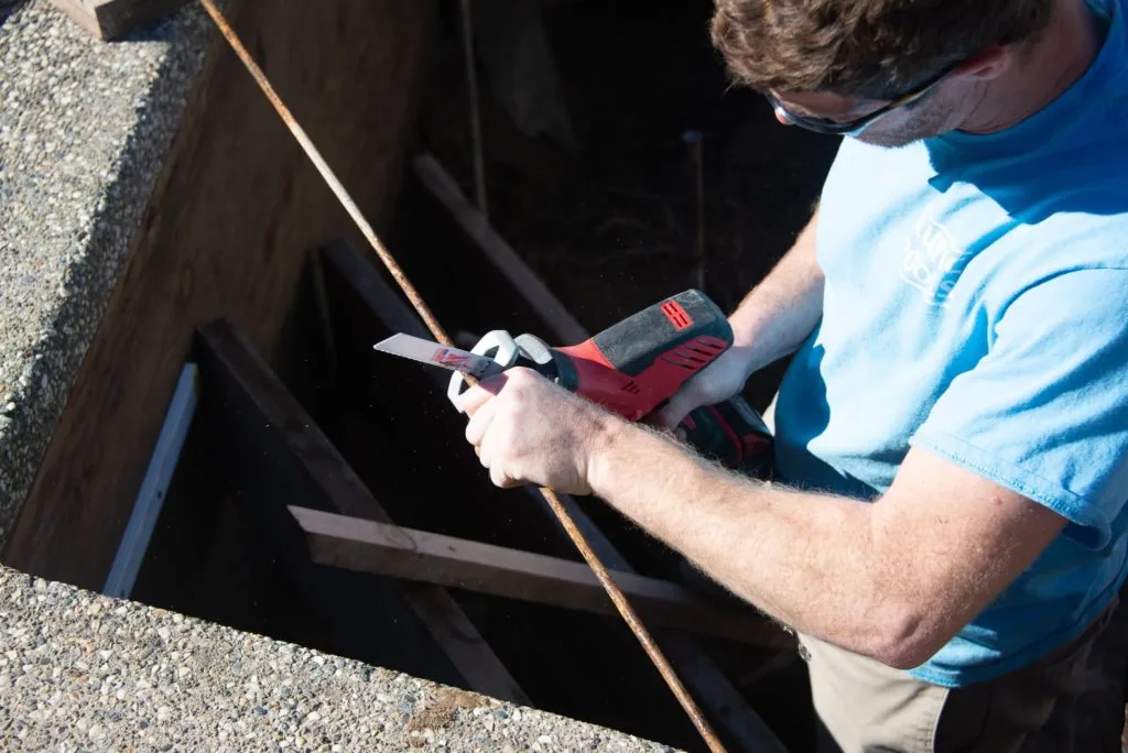 Person in blue shirt using a measuring tool on a rope over a dark pool opening