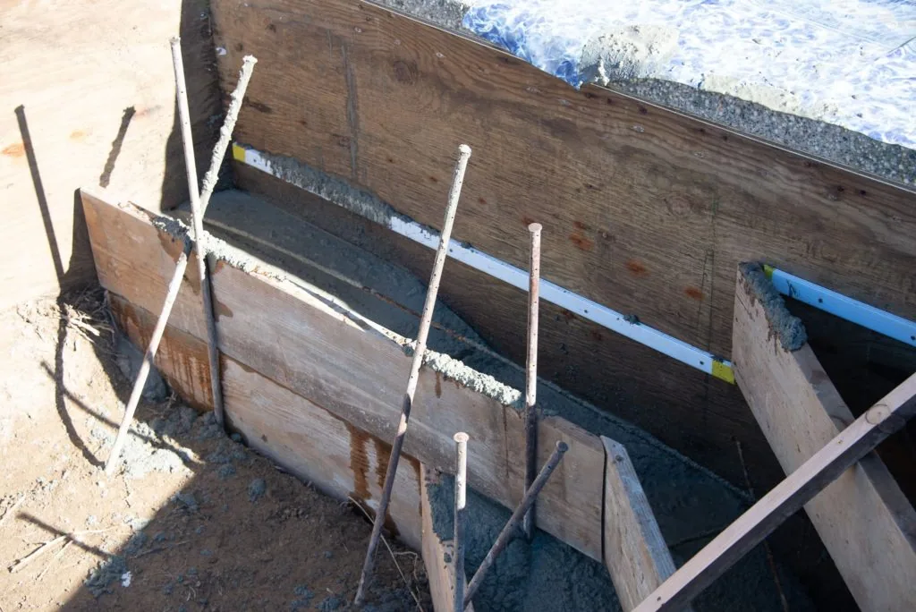 Weathered wooden boat hull with white and dark metal support posts on sandy ground