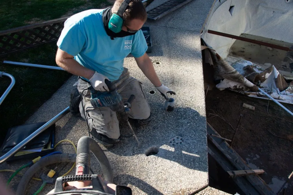 Man in blue shirt crouching on boat deck next to fishing equipment and containers