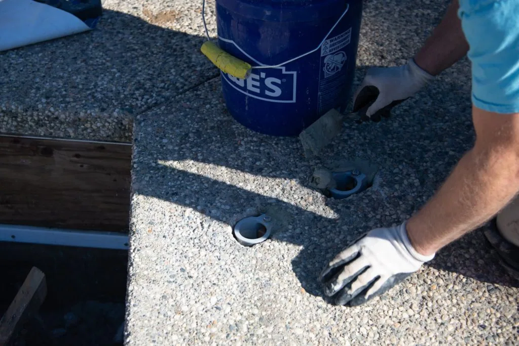 Person holding blue bucket with yellow fish next to boat deck with drain fittings
