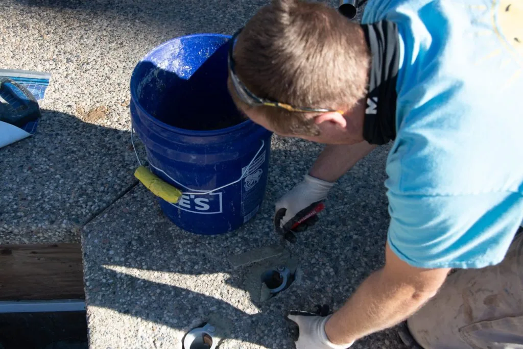 Child looking into a blue bucket on concrete surface