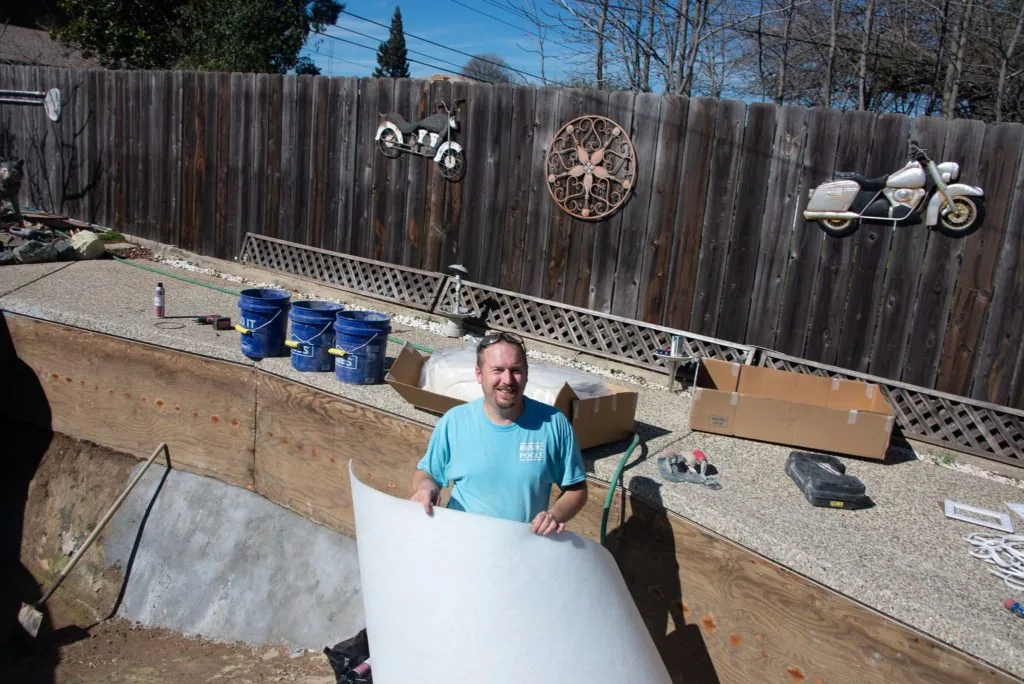 Man holding white material at construction site with wooden fence decorated with motorcycle and wheel designs