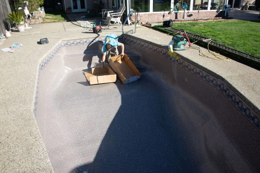 Person standing in empty residential swimming pool during renovation or maintenance work