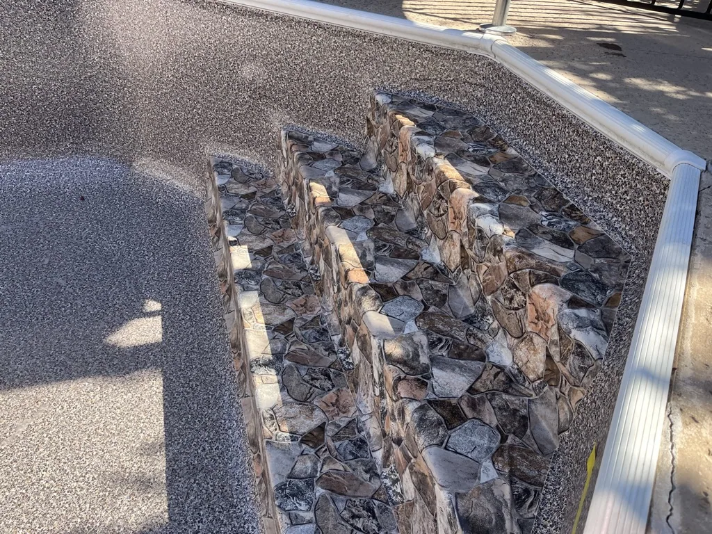 Dark mulch and bark chips arranged in rows on gravel ground with metal edging