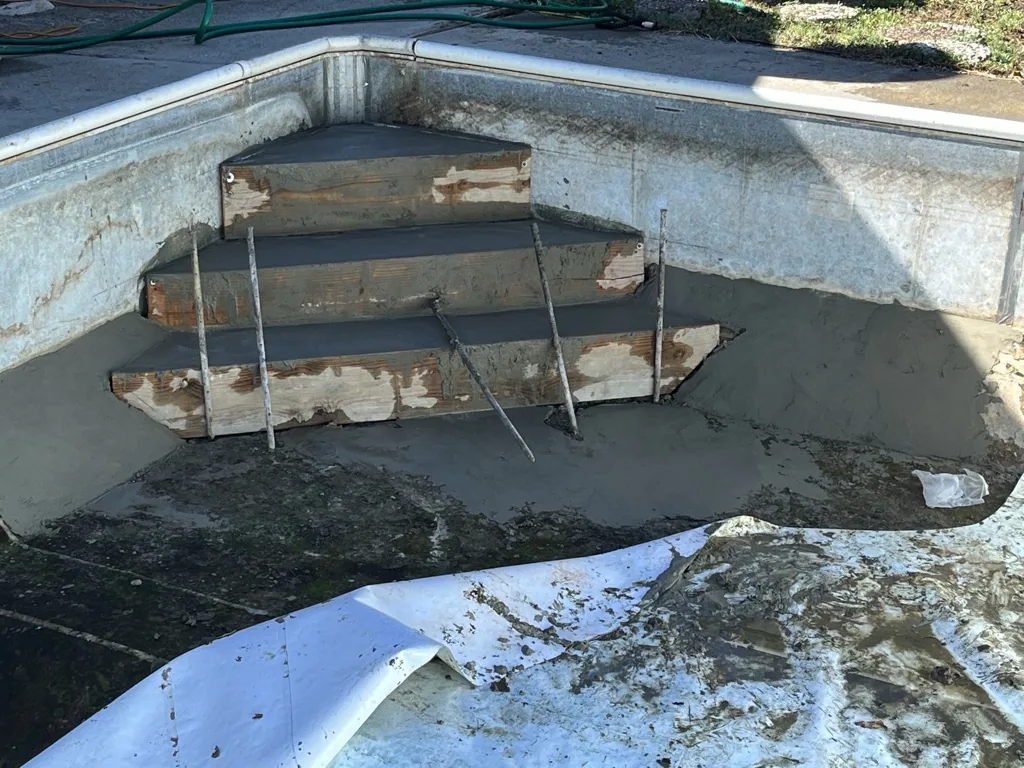 Metal livestock tank with wooden boards and metal supports submerged in dark water