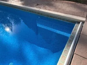 Swimming pool with bright blue water and tiled interior viewed from above the concrete deck