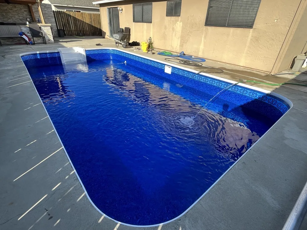 Rectangular backyard swimming pool with bright blue water and decorative tile border